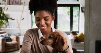 Woman working from home with dog in her lap.