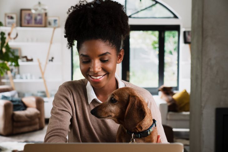 Woman working from home with dog in her lap.