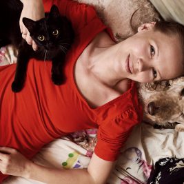 Woman in red shirt with dog and cat