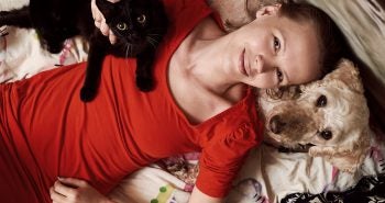 Woman in red shirt with dog and cat