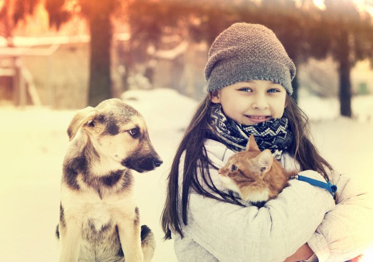 Young girl with dog and cat in the snow