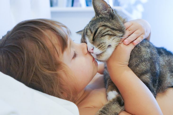 Young child snuggling with a cat.