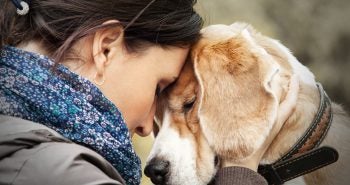 Woman touching her head to her dog's head