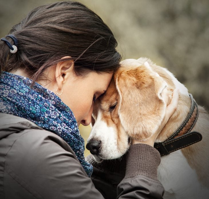 Woman touching her head to her dog's head