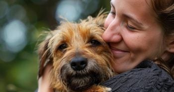 Woman hugging a small brown dog.