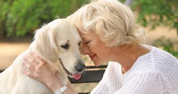Woman in white shirt hugging a white dog
