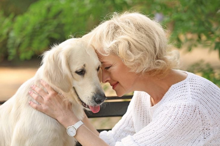 Woman in white shirt hugging a white dog