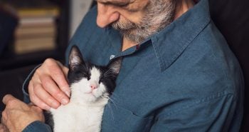 Older man holding a black and white cat