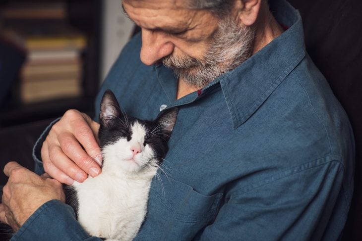 Older man holding a black and white cat