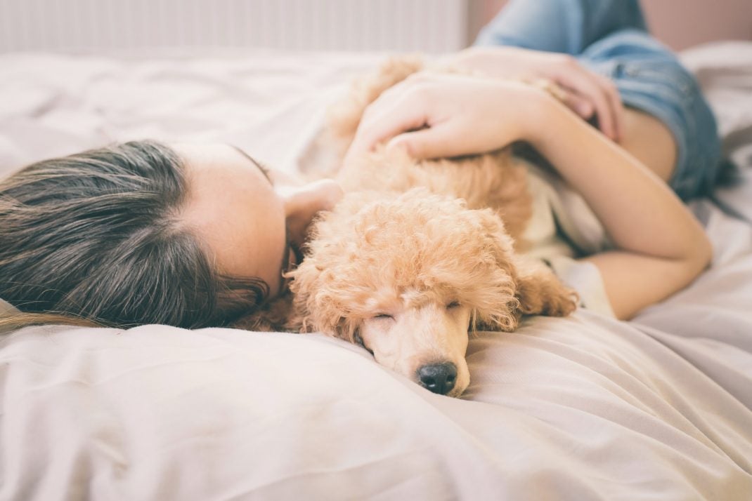 woman cuddling with a tan dog