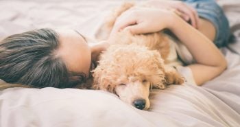 woman cuddling with a tan dog