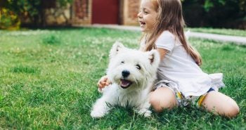 Little girl playing outside with a small white dog